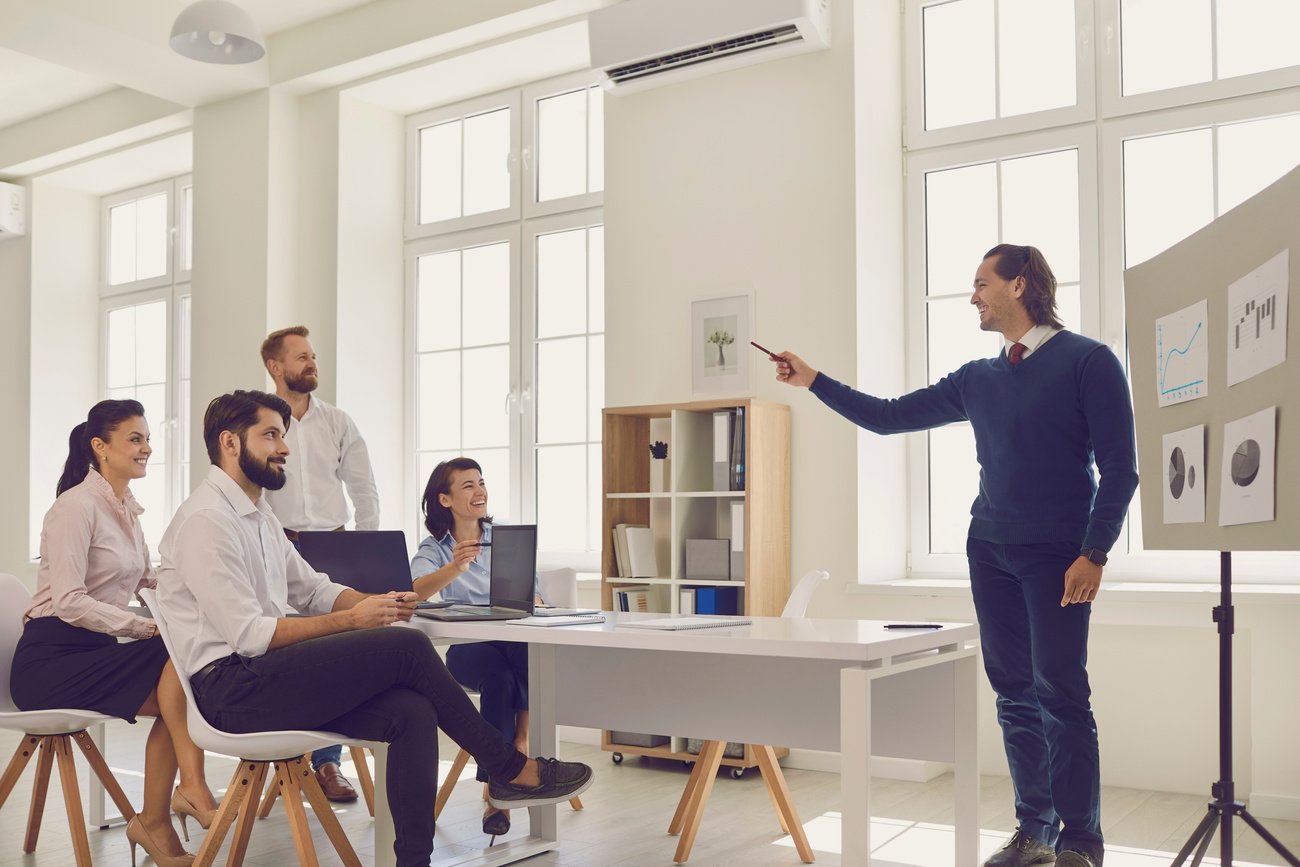 Young Sales Department Manager Asking Coworkers a Question during Presentation in a Work Meeting